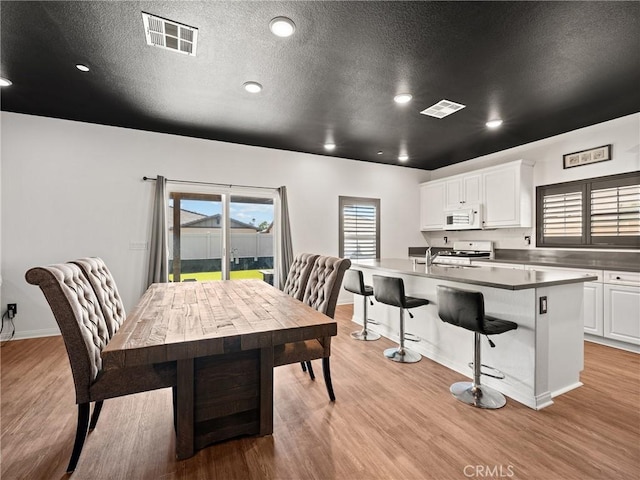 dining space featuring a healthy amount of sunlight, a textured ceiling, and light hardwood / wood-style flooring