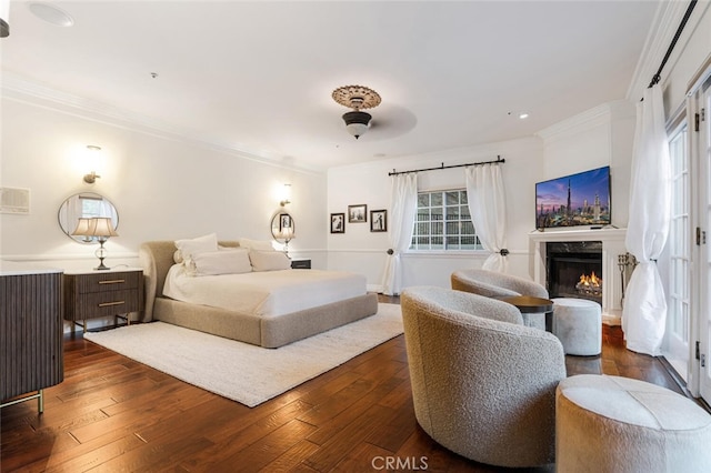 bedroom with ceiling fan, a premium fireplace, dark wood-type flooring, and ornamental molding