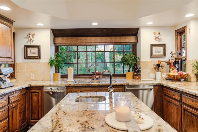 kitchen featuring light stone counters, stainless steel dishwasher, and sink