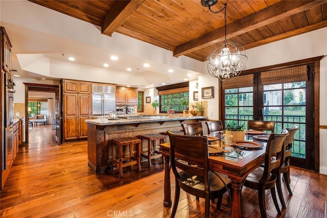 dining area featuring beam ceiling, light hardwood / wood-style floors, an inviting chandelier, and wooden ceiling