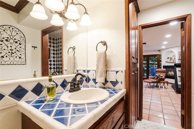 bathroom featuring tile patterned floors, decorative backsplash, vanity, and ornamental molding