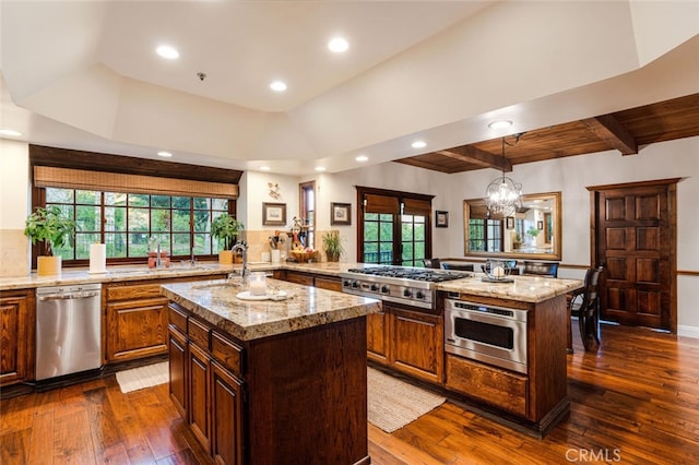 kitchen with kitchen peninsula, a kitchen island with sink, appliances with stainless steel finishes, and dark wood-type flooring