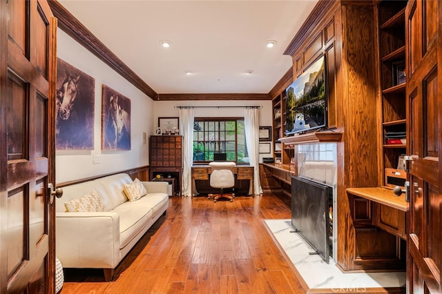 home office featuring light hardwood / wood-style flooring, built in desk, and ornamental molding