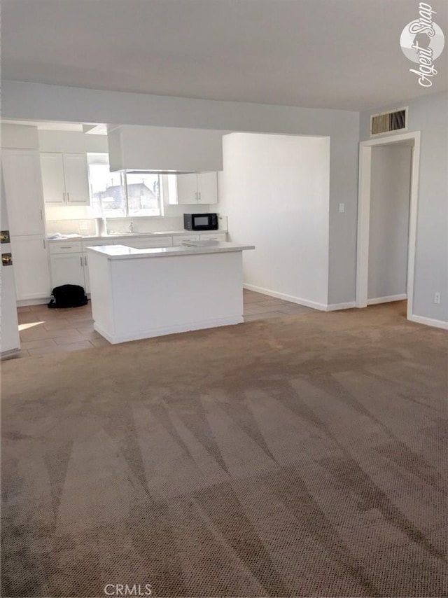 kitchen featuring a center island, white cabinets, hanging light fixtures, and light colored carpet