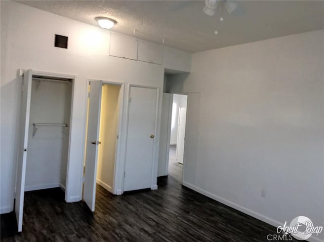 unfurnished bedroom with a textured ceiling, dark hardwood / wood-style floors, and a closet