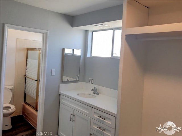 full bathroom with vanity, bath / shower combo with glass door, and toilet