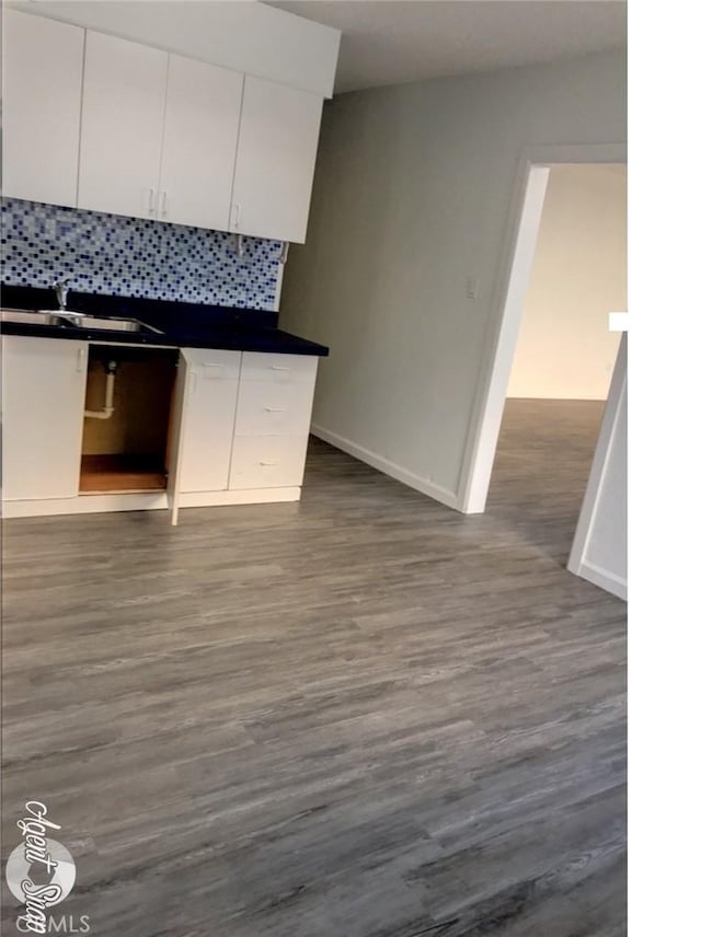 kitchen with tasteful backsplash, white cabinetry, dark wood-type flooring, and sink