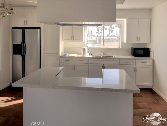 kitchen with white cabinets, stainless steel fridge, light stone countertops, and sink