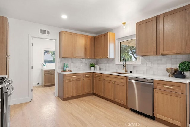 kitchen featuring appliances with stainless steel finishes, light wood-type flooring, tasteful backsplash, and sink