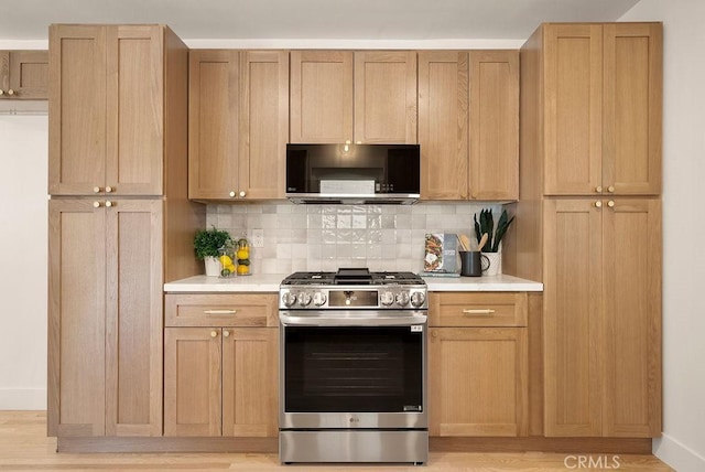 kitchen with decorative backsplash, gas range, light hardwood / wood-style flooring, and light brown cabinetry