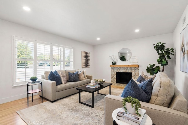 living room with a tiled fireplace and light wood-type flooring