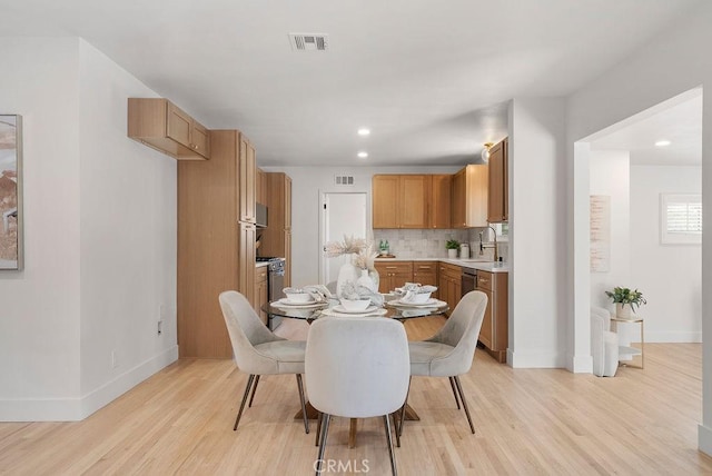 dining area with light wood-type flooring and sink