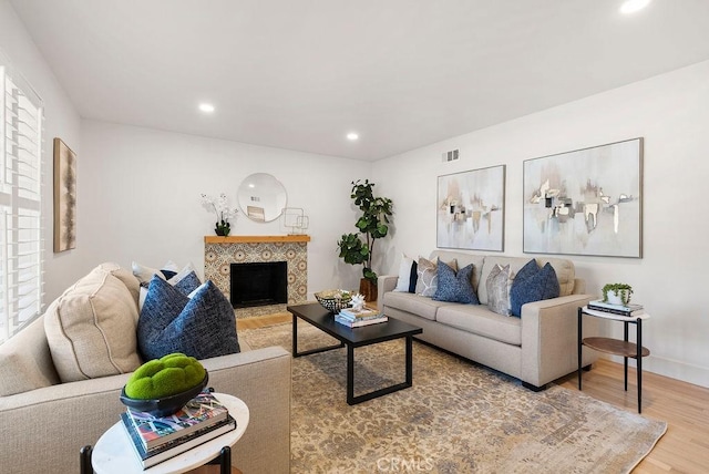 living room with hardwood / wood-style flooring and a tiled fireplace