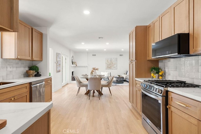 kitchen with decorative backsplash, stainless steel appliances, extractor fan, and light hardwood / wood-style floors