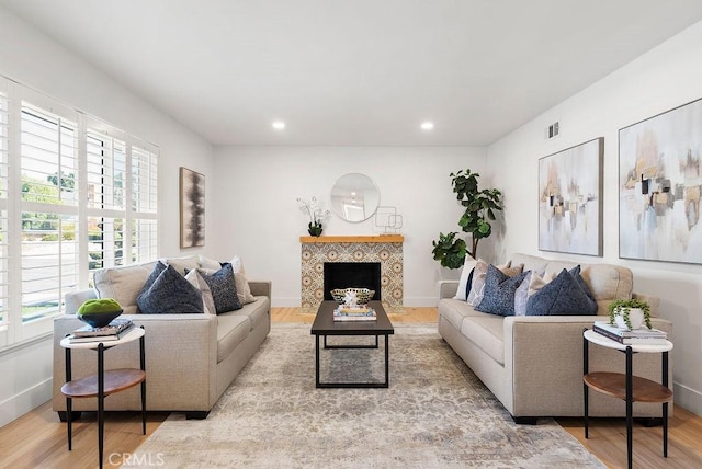 living room with light hardwood / wood-style floors and a tiled fireplace