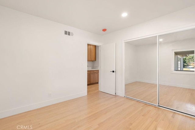 unfurnished bedroom with light hardwood / wood-style flooring and a closet