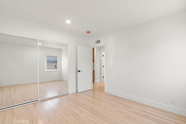 unfurnished bedroom with a closet and light hardwood / wood-style flooring