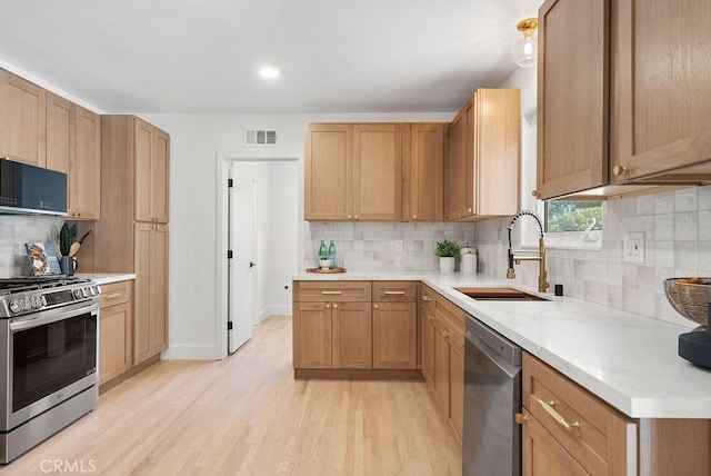 kitchen featuring decorative backsplash, sink, stainless steel appliances, and light hardwood / wood-style flooring