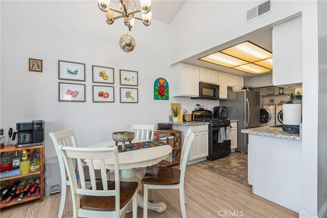 dining area featuring washer and dryer, light hardwood / wood-style floors, and an inviting chandelier