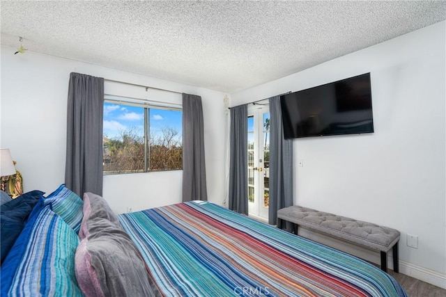 bedroom featuring wood-type flooring, a textured ceiling, and multiple windows