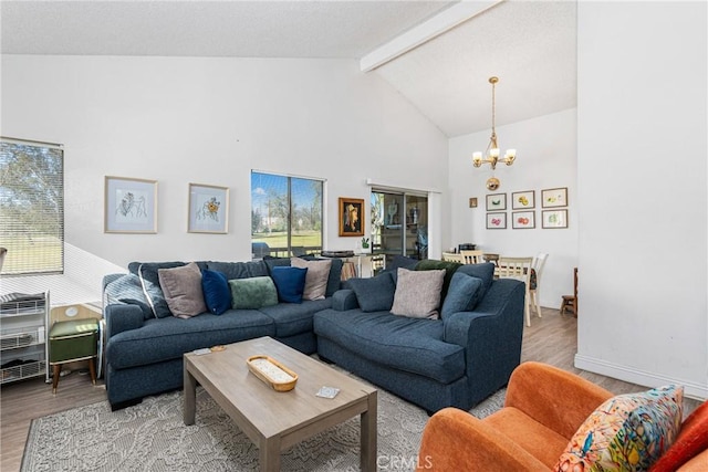 living room with beamed ceiling, plenty of natural light, light hardwood / wood-style floors, and a chandelier