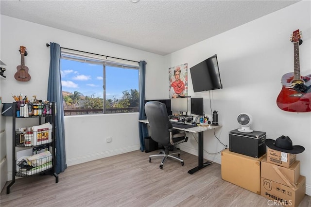 home office with light hardwood / wood-style floors and a textured ceiling