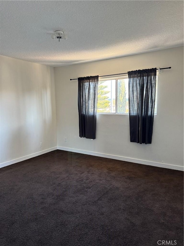 unfurnished room with dark colored carpet and a textured ceiling