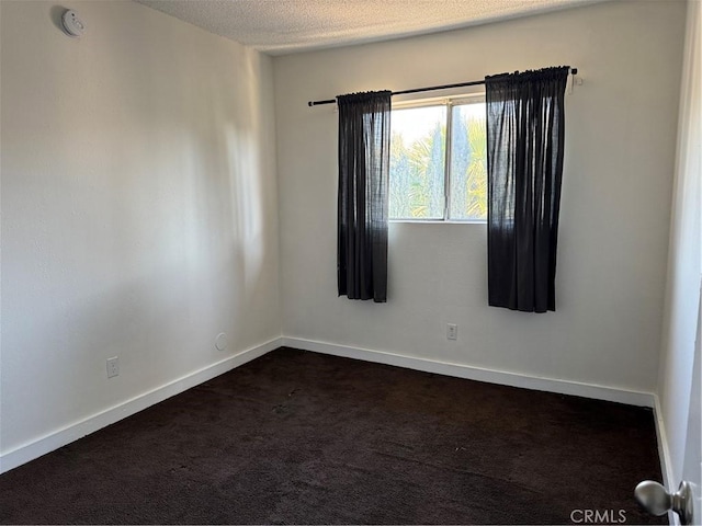 empty room featuring dark carpet and a textured ceiling