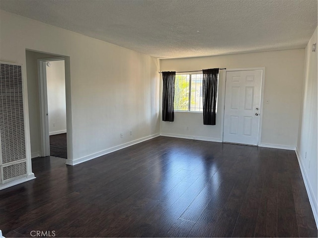 empty room with dark wood-type flooring and a textured ceiling