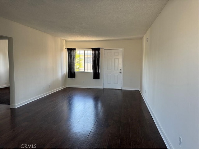 unfurnished room featuring dark wood-type flooring and a textured ceiling