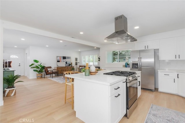 kitchen with a center island, light wood-type flooring, island range hood, white cabinetry, and stainless steel appliances