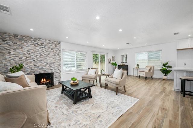 living room featuring a stone fireplace and light hardwood / wood-style flooring