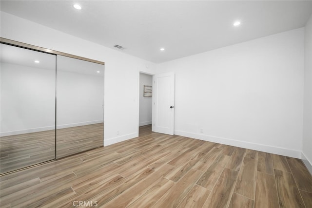 unfurnished bedroom featuring a closet and light wood-type flooring