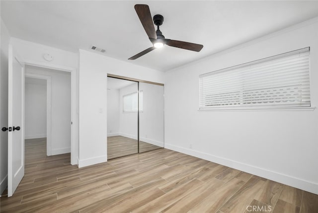 unfurnished bedroom featuring ceiling fan, a closet, and light wood-type flooring