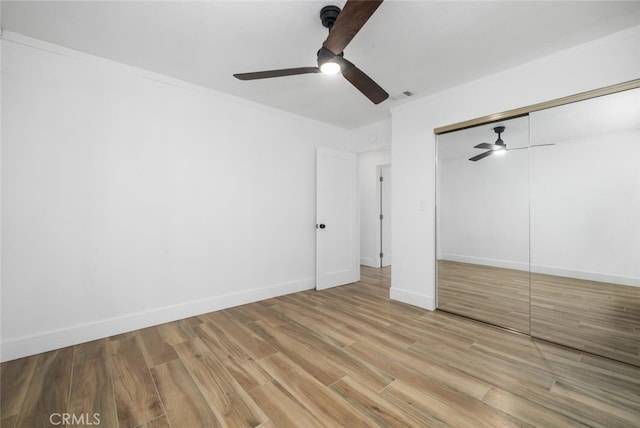 unfurnished bedroom featuring ceiling fan, a closet, and light hardwood / wood-style flooring