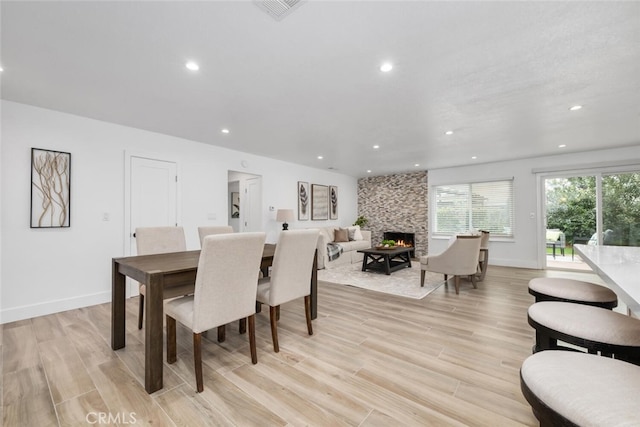 dining room featuring light hardwood / wood-style floors and a stone fireplace