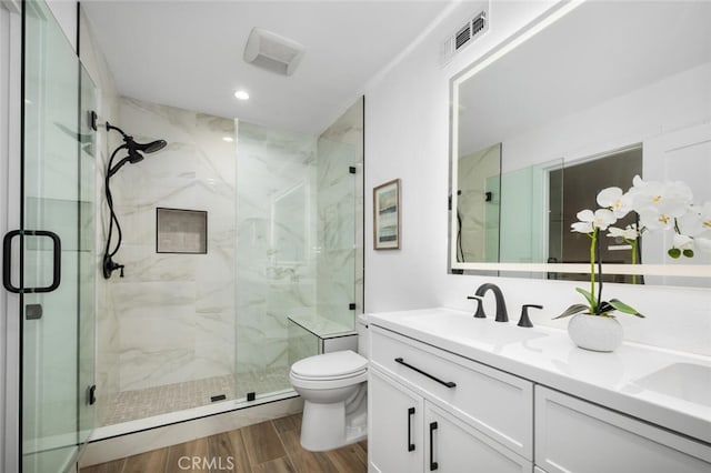 bathroom featuring vanity, a shower with shower door, and toilet