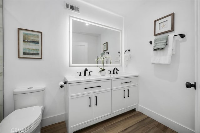 bathroom featuring vanity, wood-type flooring, and toilet