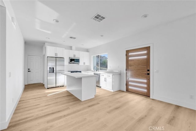 kitchen featuring white cabinetry, a center island, stainless steel appliances, and light wood-type flooring