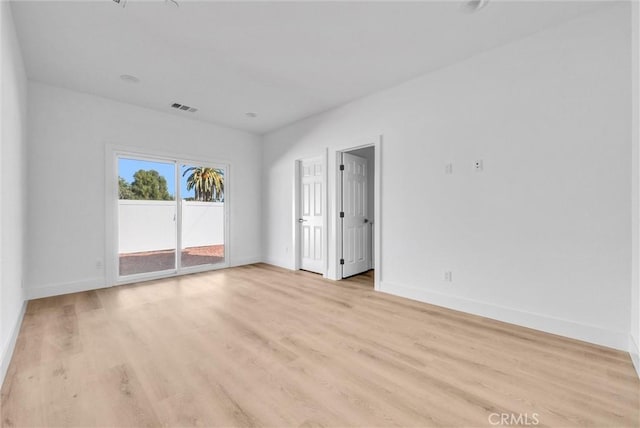 unfurnished room with visible vents, light wood-style flooring, and baseboards