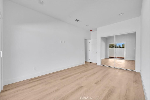 unfurnished room with wood finished floors, visible vents, and baseboards