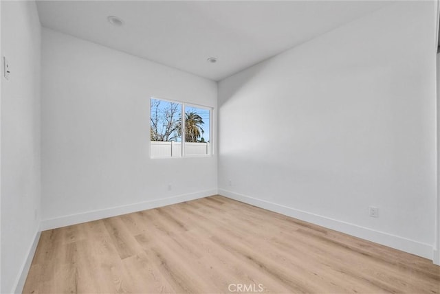 spare room featuring light wood-type flooring and baseboards