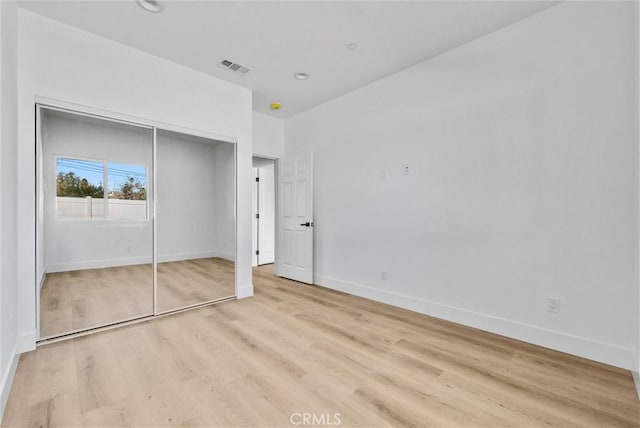 unfurnished bedroom with a closet and light wood-type flooring