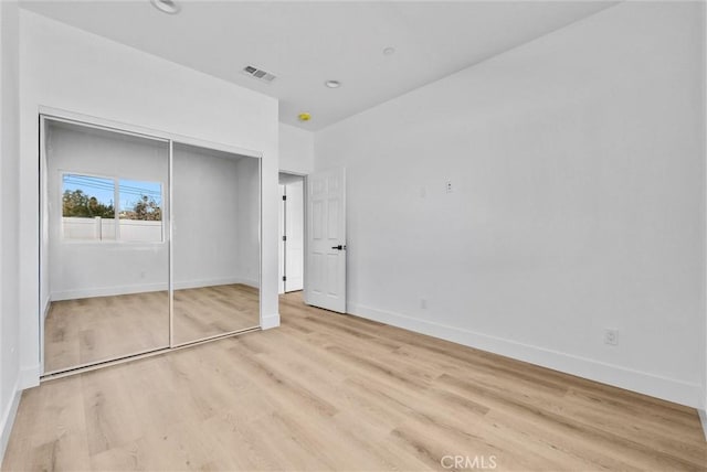 unfurnished bedroom with visible vents, a closet, light wood-style flooring, and baseboards