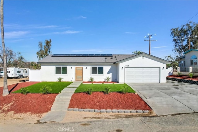 ranch-style house with driveway, a front lawn, solar panels, and stucco siding