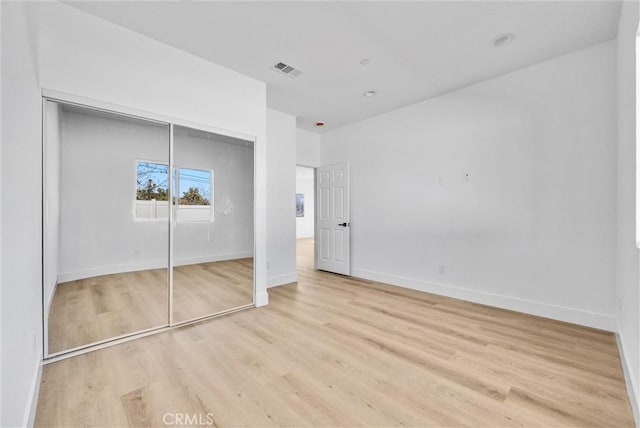 unfurnished bedroom featuring light hardwood / wood-style floors and a closet