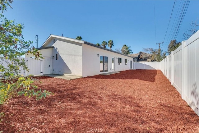 rear view of property featuring a patio area, a fenced backyard, and stucco siding