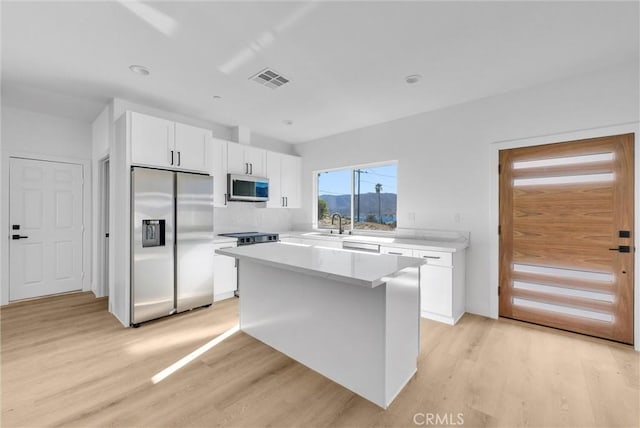 kitchen featuring white cabinets, light wood-type flooring, a center island, and stainless steel appliances