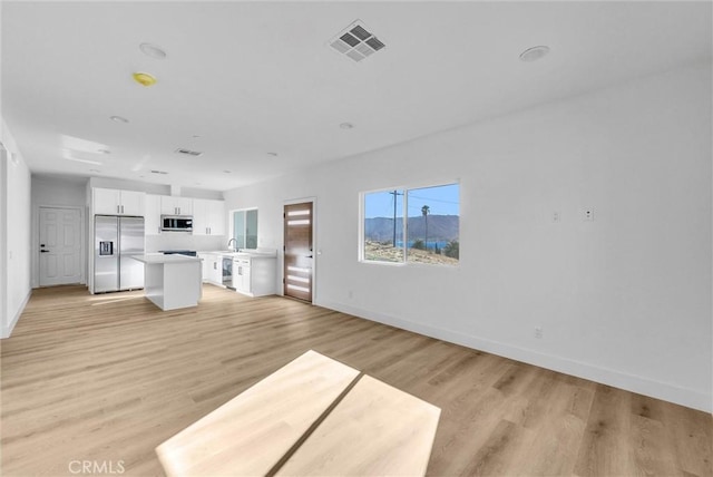 unfurnished living room featuring light hardwood / wood-style flooring and sink