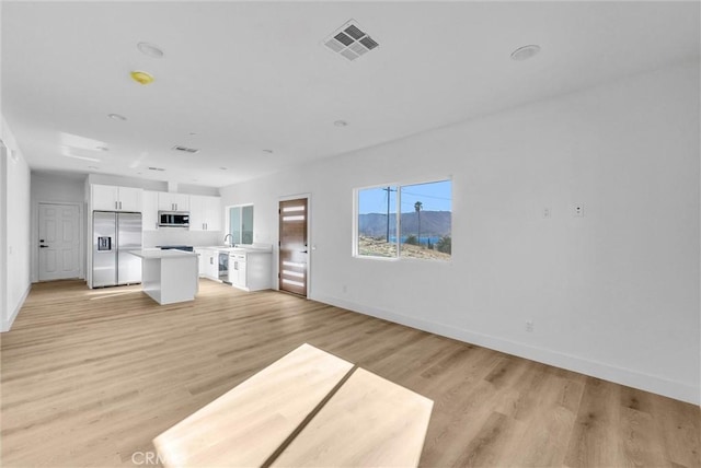 unfurnished living room featuring light wood-style floors, baseboards, and visible vents